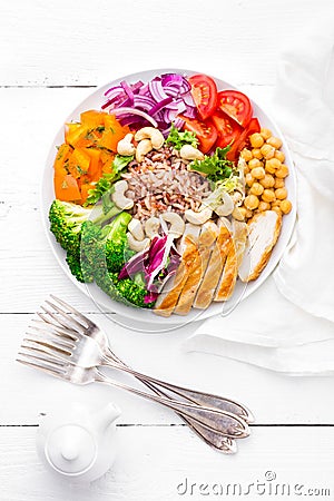 Buddha bowl dish with chicken fillet, brown rice, pepper, tomato, broccoli, onion, chickpea, fresh lettuce salad, cashew and walnu Stock Photo