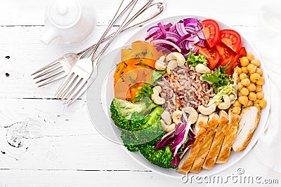 Buddha bowl dish with chicken fillet, brown rice, pepper, tomato, broccoli, onion, chickpea, fresh lettuce salad, cashew and walnu Stock Photo