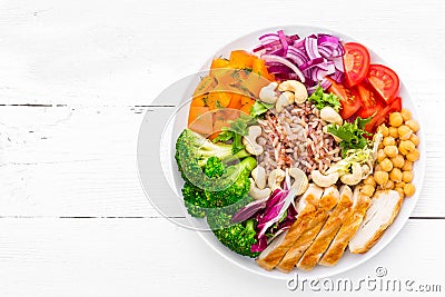 Buddha bowl dish with chicken fillet, brown rice, pepper, tomato, broccoli, onion, chickpea, fresh lettuce salad, cashew and walnu Stock Photo