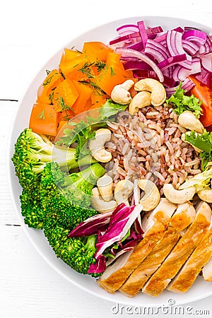 Buddha bowl dish with chicken fillet, brown rice, pepper, tomato, broccoli, onion, chickpea, fresh lettuce salad, cashew and walnu Stock Photo