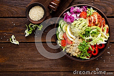 Buddha bowl dish. Healthy balanced lunch with quinoa, grilled chicken meat, lettuce salad, pepper, cucumber, tomato and avocado gu Stock Photo