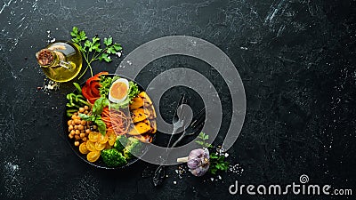 Buddha bowl: pumpkin, broccoli, egg, tomatoes, carrots, paprika in a black plate on a black background. Stock Photo