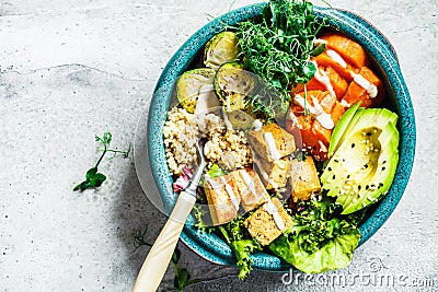 Buddha bowl with quinoa, tofu, avocado, sweet potato, brussels sprouts and tahini dressing, top view. Healthy vegan food concept Stock Photo