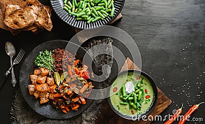 Buddha bowl salad with salmon, red quinoa, baked vegetables, micro greens, peas cream soup with green beans in bowl on dark wooden Stock Photo