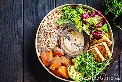 Buddha bowl with tofu, avocado, rice, seedlings, sweet potato and tahini dressing Stock Photo