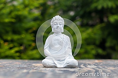 Buddha - ceramic statuette budha on green background. Buddhism, meditation and yoga concept Stock Photo