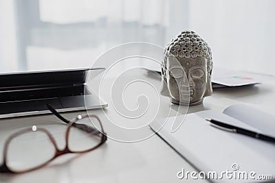 Buddha head, eyeglasses, notepad and laptop Stock Photo