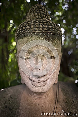 Buddha sculpture with back light from sun through leaves curtain. Stock Photo