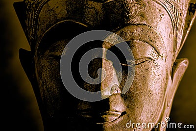 Buddhism. High contrast Buddha face statue close-up. Dramatic side light Stock Photo