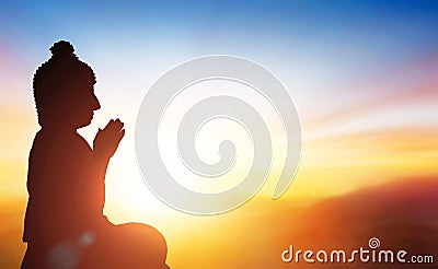 Buudha head and side body statue with sunset background as golden aura. Stock Photo