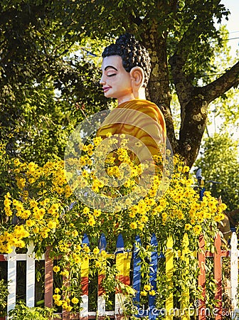 Buddhist Figure in Garden with Yellow Flowers Stock Photo