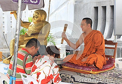 Buddhist monk blessing people ouside some buddhist temple, Thailand Editorial Stock Photo