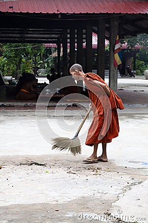 Buddhist monk brooming the floor outside Editorial Stock Photo