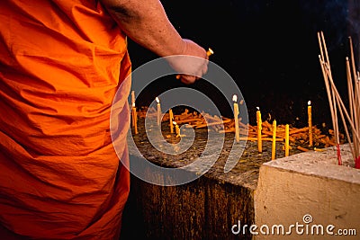 Buddhist monk hands holding candle and lighting up candle in temple Stock Photo