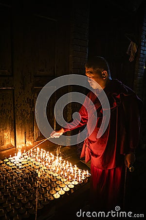 Buddhist monk lights a candle Editorial Stock Photo