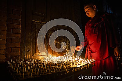 Buddhist monk lights a candle Editorial Stock Photo