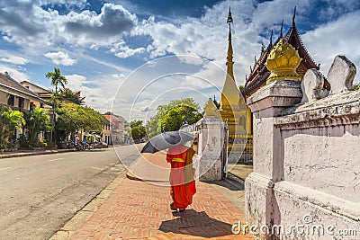 A Buddhist monk walks by the Wat Sen Temple in Luang Prabang, Laos Editorial Stock Photo