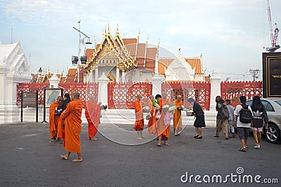 Buddhist monks collect food and offerings at the temple Wat Benchamabophit in the early morning. Bangkok,Thailand Editorial Stock Photo