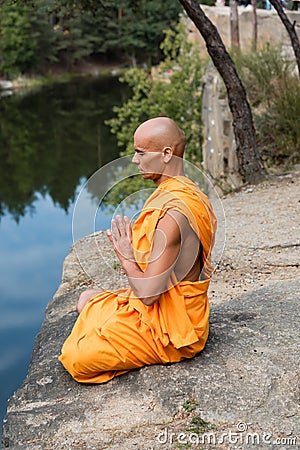 buddhist in orange robe meditating in Stock Photo