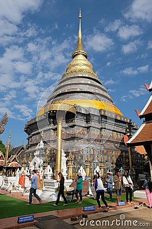 Buddhist people circle walk around main chedi at Wat Phra That Lampang Luang in Lampang province Editorial Stock Photo