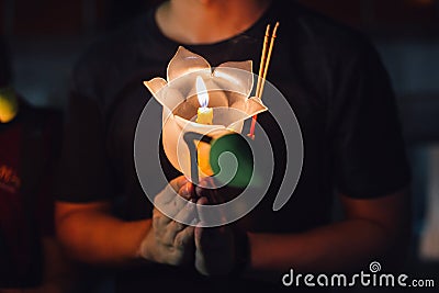 Buddhist praying with incense sticks, lotus flower and candles on holy religion day of Vesak at night. Stock Photo