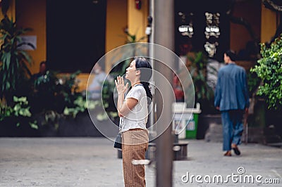 Buddhist worshiper praying at the altars of Buddhist idols with incense and chant in Hanoi, Vietnam. Editorial Stock Photo