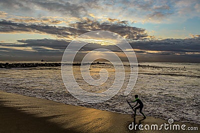 A Young Boy Prepares to Ride a Wave in Redondo Beach on a Rainy Evening, Los Angeles County, California Editorial Stock Photo