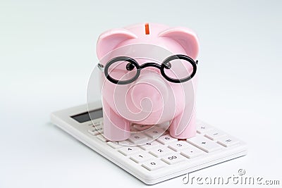 Budget, cost or investment calculation and financial activity concept, pink piggy bank wearing glasses on white calculator on Stock Photo