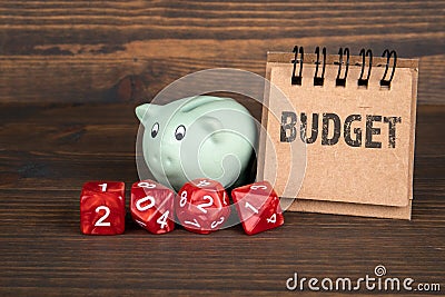 2021 BUDGET. Family, health and politics concept. Red dice, piggy bank and notebook Stock Photo