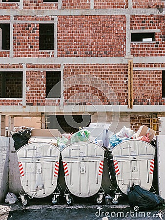 Budva, Montenegro - 05 august 2023: Overflowing trash cans stand next to a house under construction Editorial Stock Photo