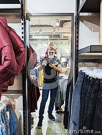 Budva, Montenegro - 07.07.22: Dad with a little girl on his shoulders is photographed in a mirror in a clothing store Editorial Stock Photo