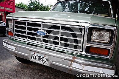 Close-up of radiator grille, headlights, hood and chrome bumper with rust of Ford F-100 pickup truck Editorial Stock Photo