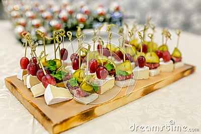 The buffet at the reception. Assortment of canapes on wooden board. Banquet service. catering food, snacks with cheese, jamon and Stock Photo