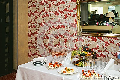 Buffet table near the wall with colored wallpaper and a large mirror Stock Photo