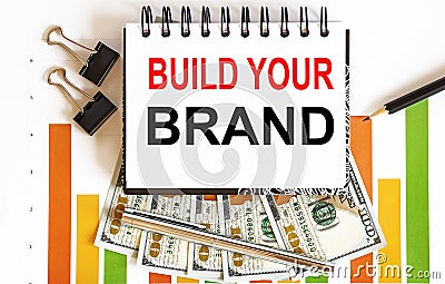 BUILD YOUR BRAND text on a white background with chart,pencil and dollars Stock Photo