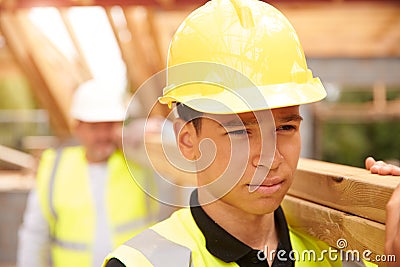 Builder And Apprentice Carrying Wood On Construction Site Stock Photo