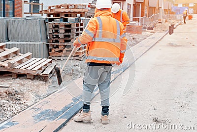 Builder block paved footpath and filling joints with sand Stock Photo