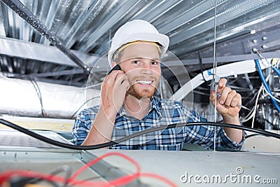 Builder calling plumber while fixing ceiling Stock Photo