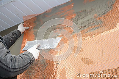 Builder contractor plastering wall with spatula, fiberglass mesh, plaster mesh after foam rigid insulation Stock Photo