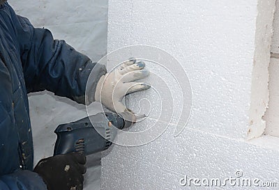 Builder drilling wall for installing anchors to hold rigid insulation foam board. Stock Photo