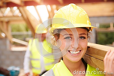 Builder And Female Apprentice Carrying Wood On Site Stock Photo