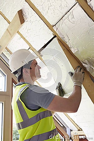 Builder Fitting Insulation Boards Into Roof Of New Home Stock Photo