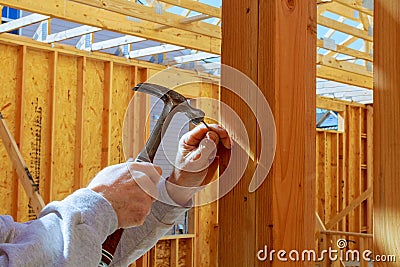 Builder hammers a nail into a wooden beam Stock Photo