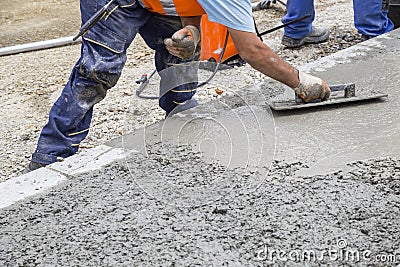 Builder hand leveling concrete with trowel Stock Photo