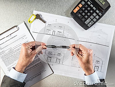Builder hands with key and housing draft thinking about negotiation Stock Photo