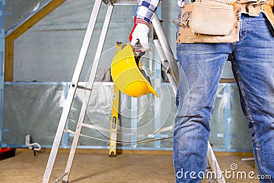 Builder handyman with yellow safety helmet and tool belt on atti Stock Photo