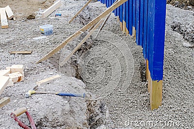 Builder installing rail slippers painted blue into semi-dry concrete to form a secure barrier around new school playground as part Stock Photo