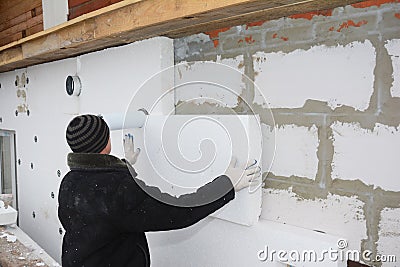 Builder installing rigid styrofoam insulation board for energy saving. Editorial Stock Photo