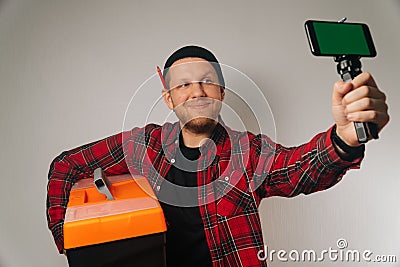 Builder is a man of Caucasian portrait as taking selfie on smartphone Stock Photo