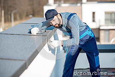 Builder mounting metal cover on the parapet of a new building Stock Photo